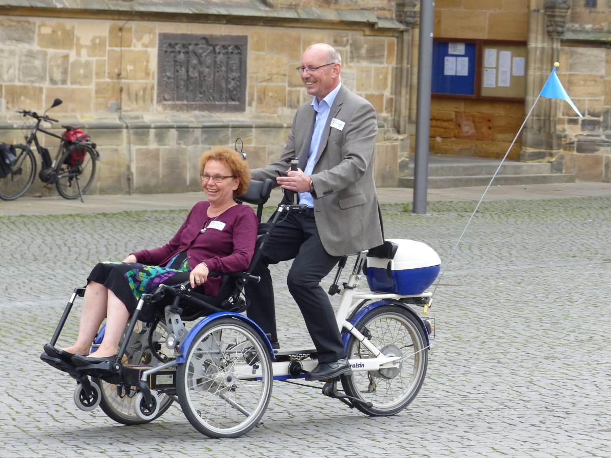 Zwei Besucher testen das Rollstuhlfahrrad
