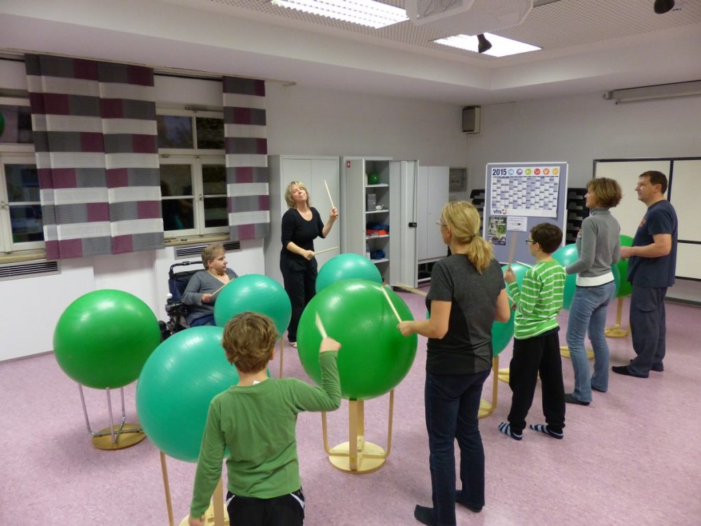 Kurs·teilnehmer trommeln auf Bällen