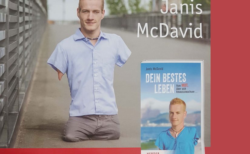 Plakat von Janis McDavid auf einer Brücke. Neben Janis McDavid ist sein Buch 'Dein bestes Leben' abgebildet.