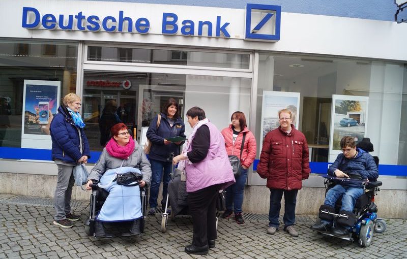 Eine Gruppe von Teilnehmern vor einer Filiale der Deutschen Bank
