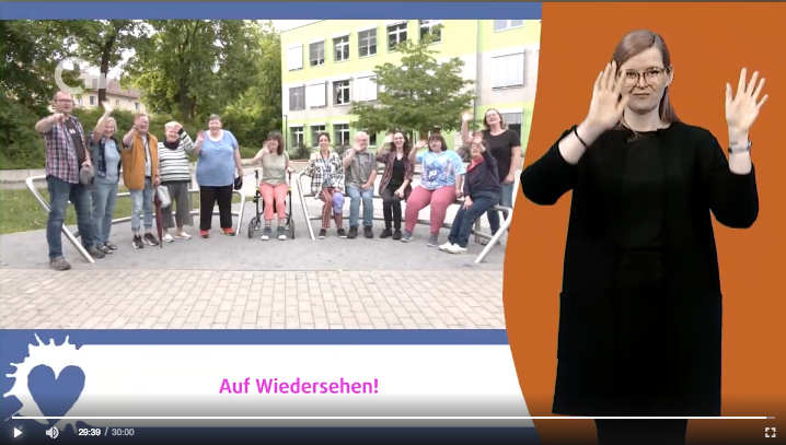 Ein Bildschrimfoto von einer Fernsehsendung bei OTV. Rechts steht eine Gebärdensprachdolmetscherin. Links winkt eine Gruppe fröhlich in die Kamera. Darunter ist das Zeichen vom Wundernetz und der Text: Auf Wiedersehen!